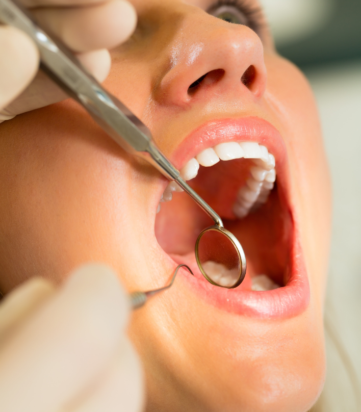 Zahnarzt kontrolliert mit Spiegel die Zähne der Patientin